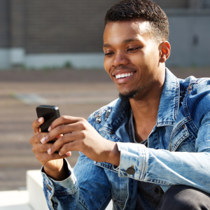 Man with denim jacket holding a cellphone and texting